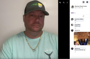 facebook profile picture dated 7/11/22 for shannon shane coats. he wears a hat with the state of nc on it, a light blue teeshirt, a gold chain with a gold ring hanging from it, has very pink skin and glassy eyes.